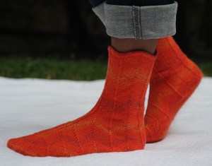 Double decreases and increases form arrow points at the cuff, while bending color variegations into zigzags along the way.